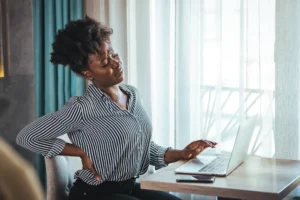A woman sitting at her desk with back pain.
