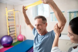 Male patient doing resistance band therapy with doctor, receiving personalized treatment from an Oklahoma City pain management clinic.