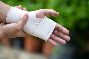 Person with a wrapped wrist holding their hand in pain, showing common upper extremity injuries managed by Oklahoma pain doctors.