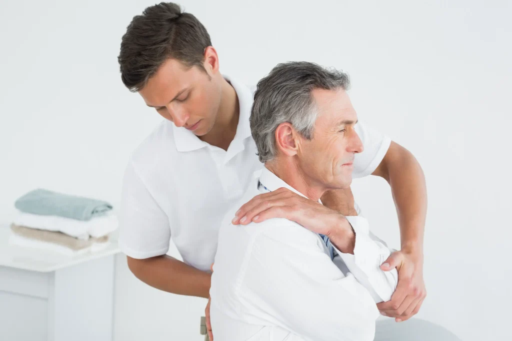 A healthcare professional assists an older man with back therapy, illustrating the hands-on treatment approach common to chiropractors.