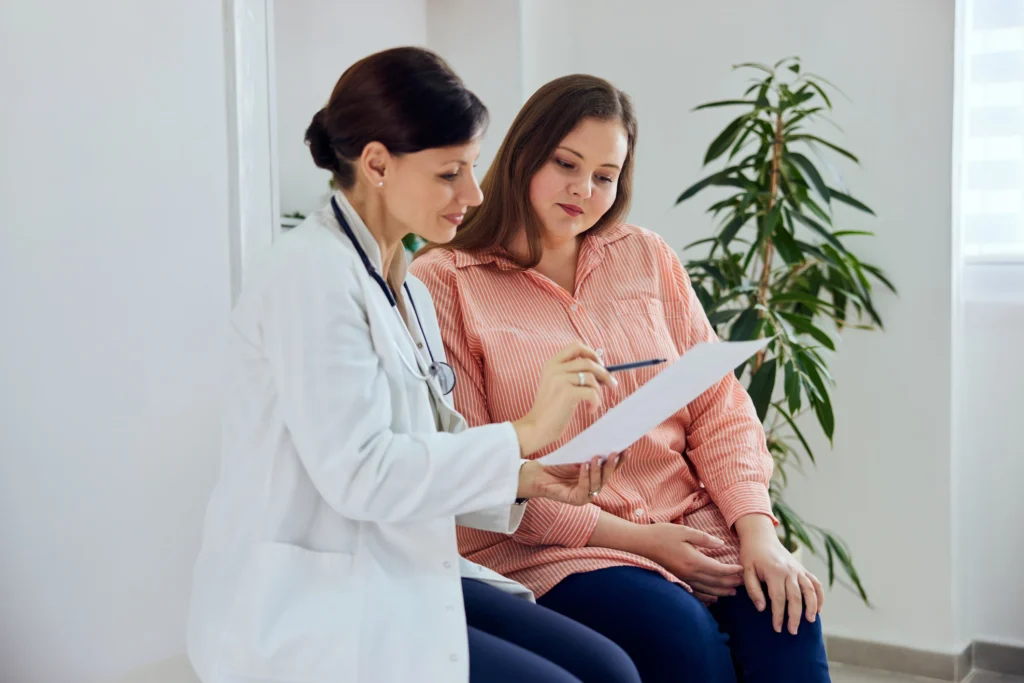 Female doctor reviewing medical paperwork with a patient in a clinic setting, illustrating the consultation process often involved in chiropractic care.