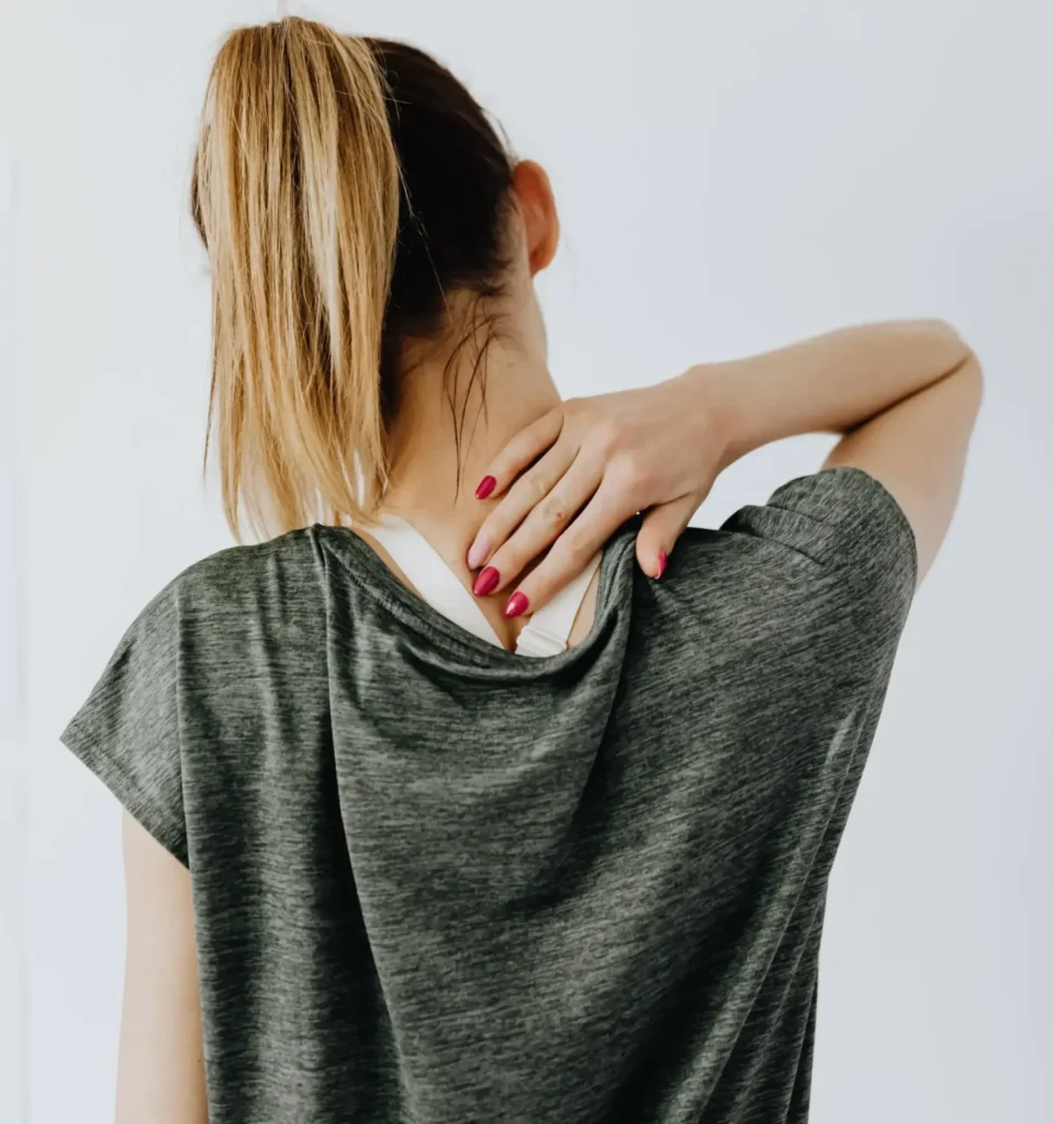 Woman holding the back of her neck in pain, suggesting discomfort or injury such as whiplash.